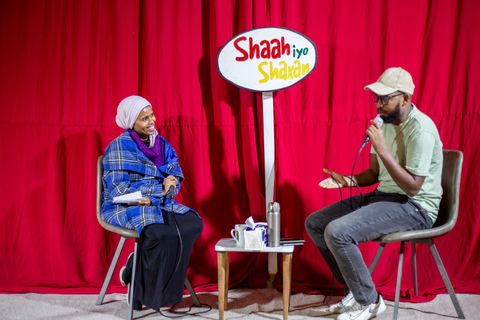 Host and guest with the Shaah iyo Shaxan sign in front of the red curtain