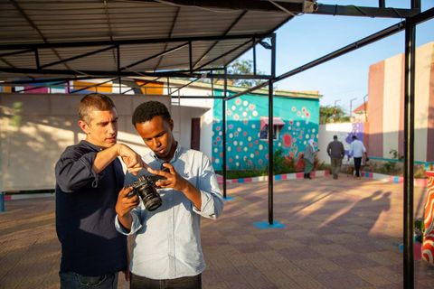 Two men looking at a camera together in the courtyard