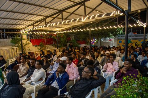 Audience under the string lights at the open mic