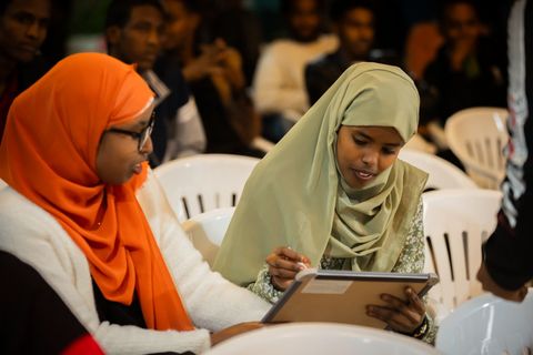 Two audience members reading during the open mic
