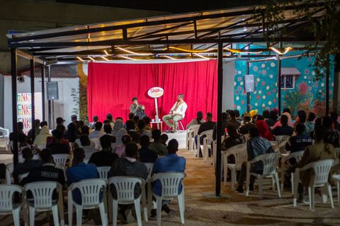 Audience facing the red-curtain stage