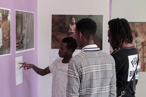 Visitors pointing at photographs at the IOM photo exhibition
