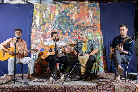 Four musicians with guitars and a drum on the open mic stage