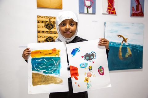 Young participant holding up her paintings