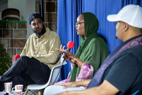 Guest, host and co-host talking in front of the blue curtain